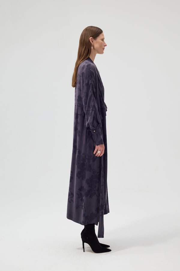 Woman wearing a long dark gray dress on a white background