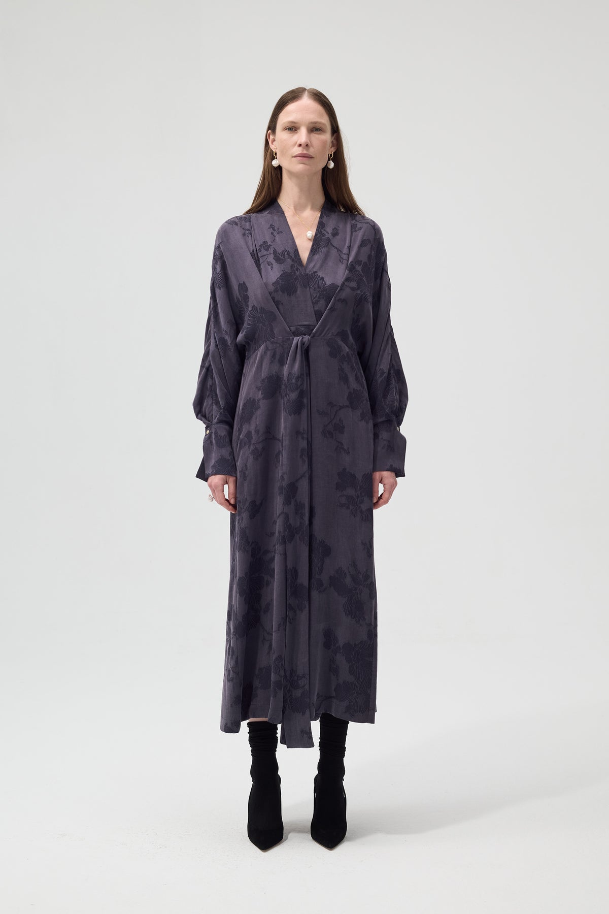 Woman wearing a long, dark patterned dress on a white background