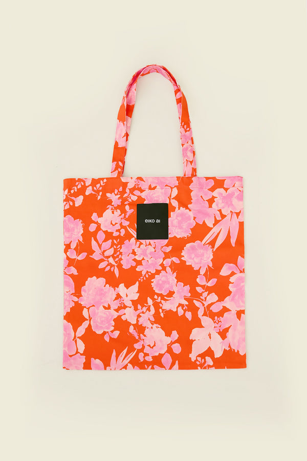 Floral tote bag with a visible brand logo on a beige background