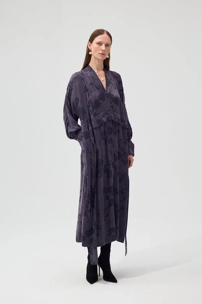 Woman wearing a long, dark purple robe against a white background